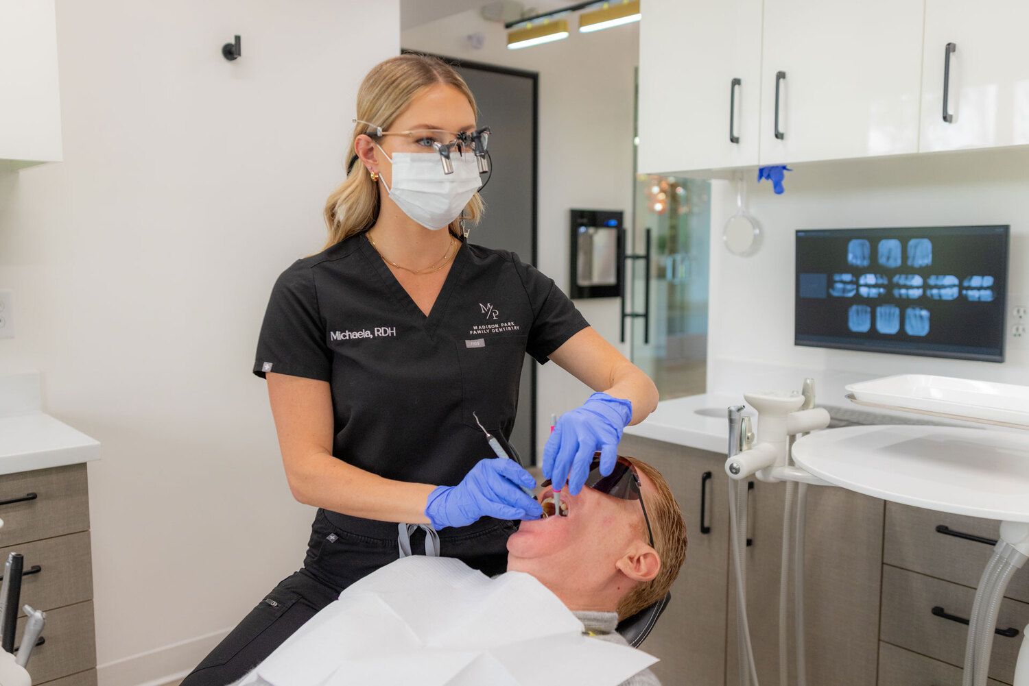 Team member at Madison Park Family Dentistry showing dental scan to smiling patient on screen