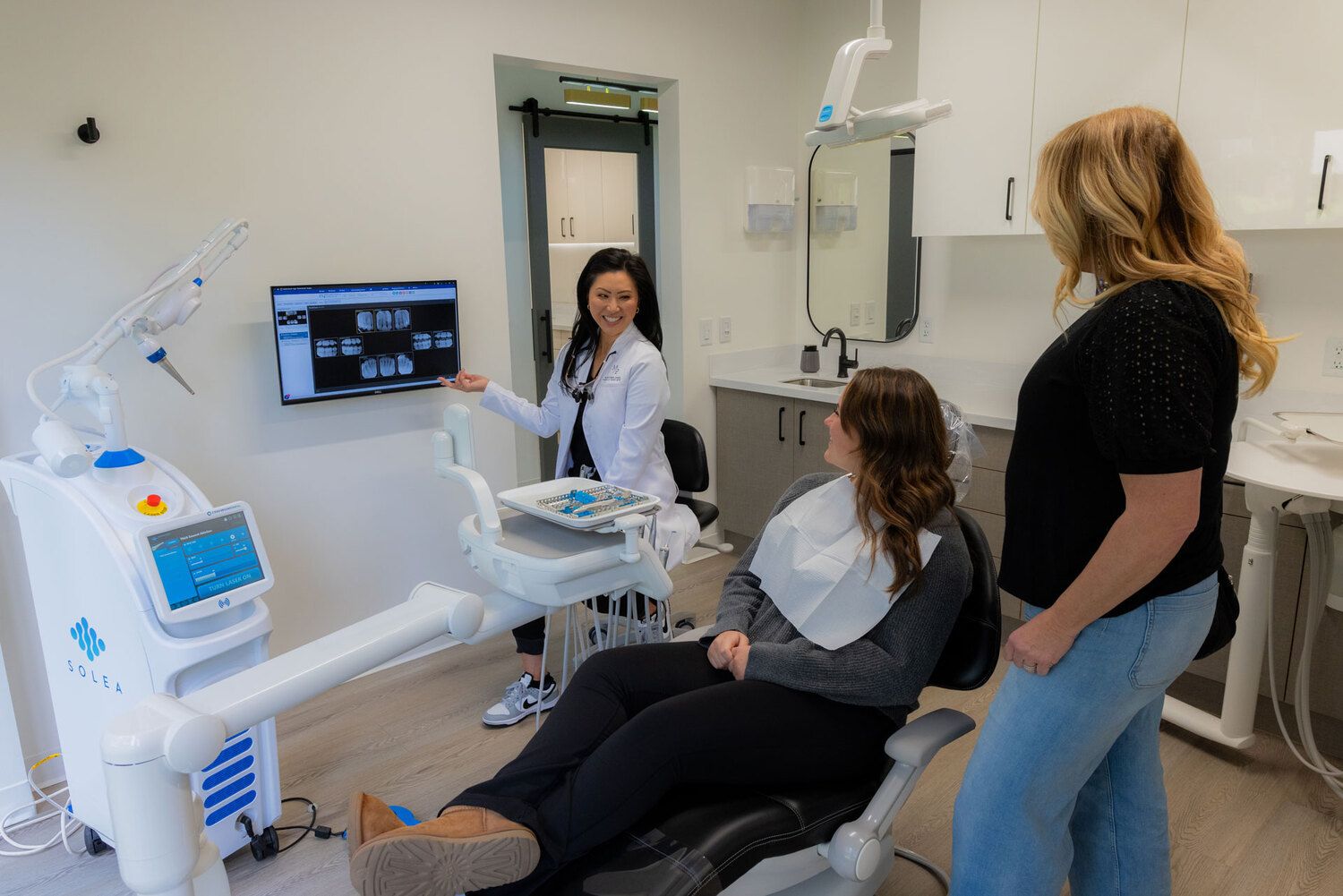Dentist showing dental X-rays to patient and companion at Madison Park Family Dentistry