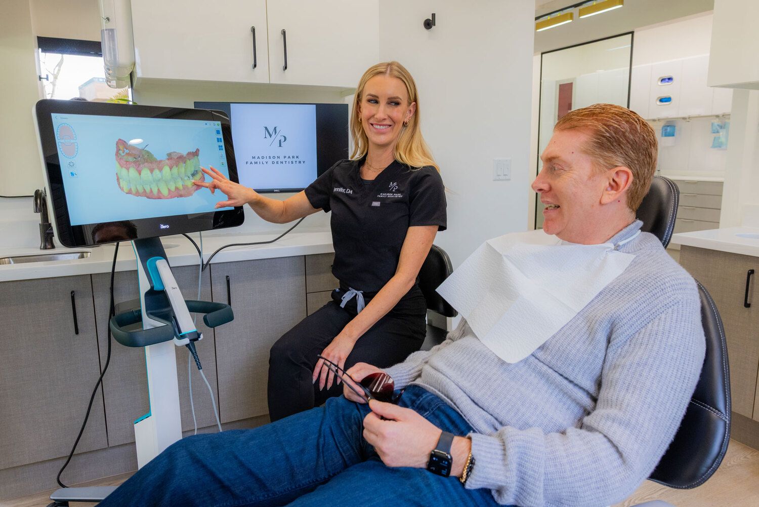 Team member at Madison Park Family Dentistry showing dental scan to smiling patient on screen